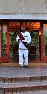 Tony Sparkes Wildlife & Photo Safaris - Hamiltons-Tented-Camp - Old Fashioned Nostalgia, blackman dressed up in old fashioned clothes and sash with fez.