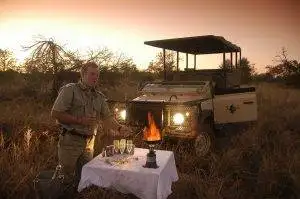 Imbali-Safari-Lodge-Game-Drive at sunset man standing with drinks on a table