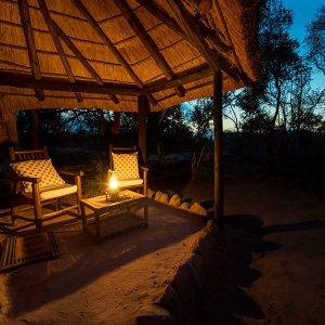2 chairs outside a safari tent at night with oil lamp lit